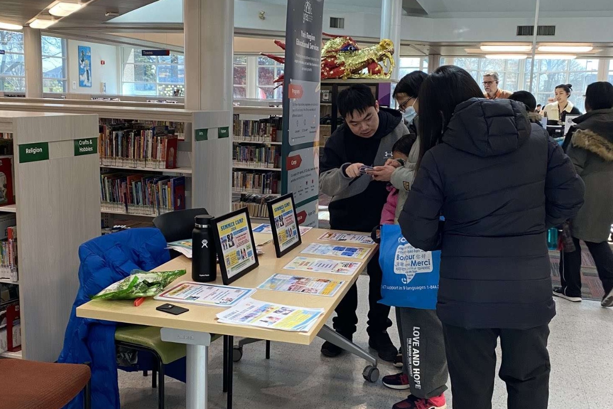 Community members interacting with volunteers at info session booth